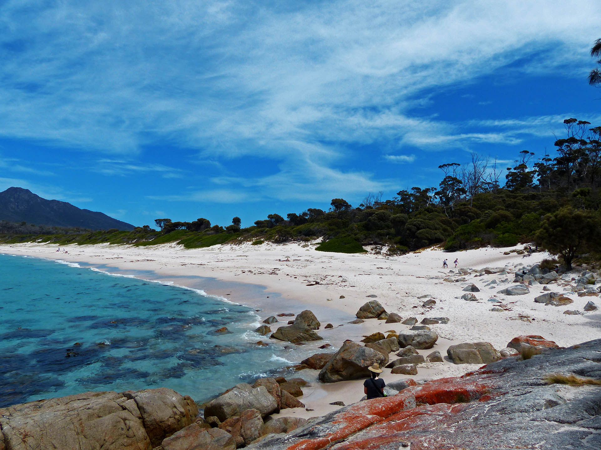 Alina sitzend auf den roten Steinen vor dem Strand an der Wineglass Bay